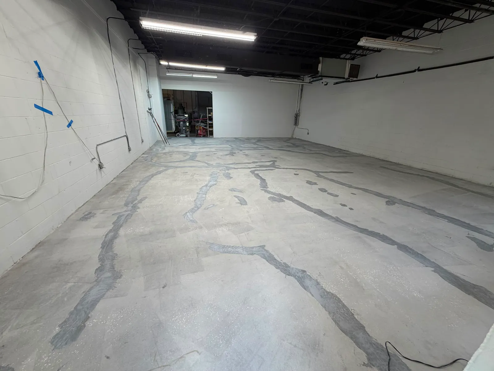 Cracked and stained bare concrete warehouse floor before coating