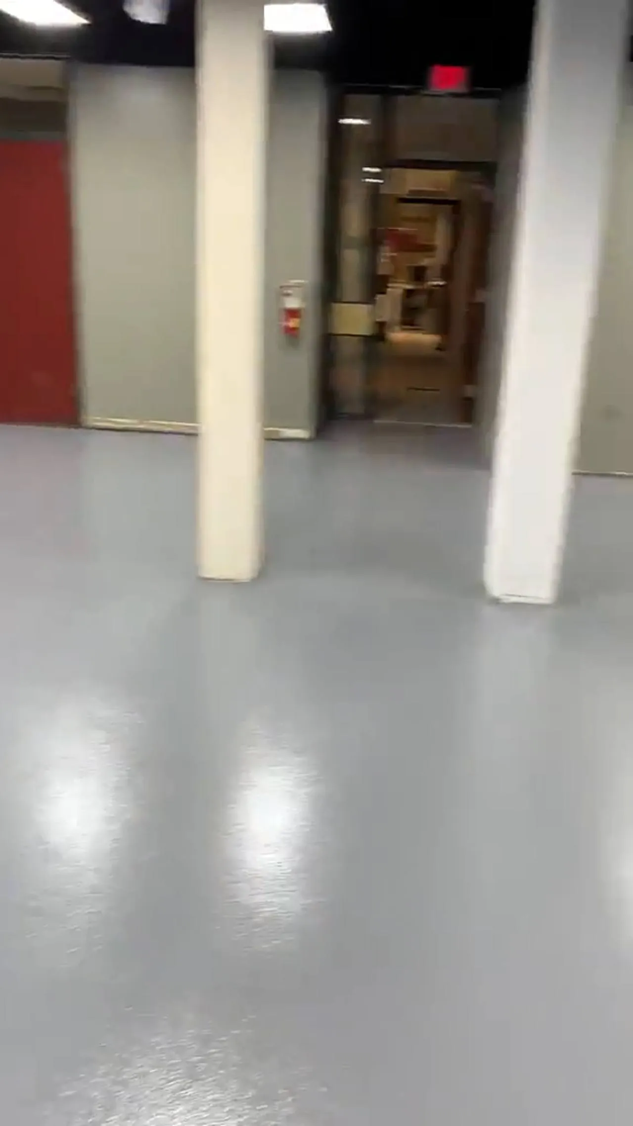Glossy grey resinous floor running through an open commercial build-out with sage-green walls and red structural columns