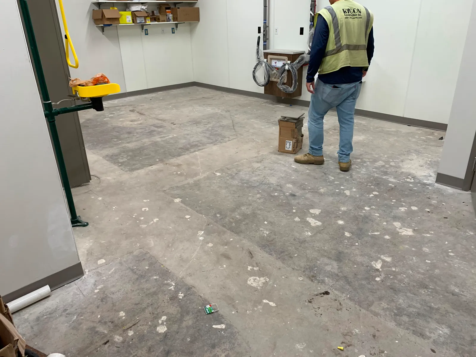 Crew member preparing a raw concrete slab before coating in a commercial build-out