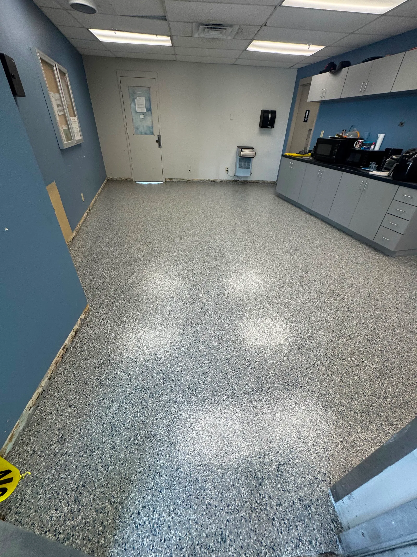 Light decorative flake floor with a blue accent wall in a commercial kitchen area