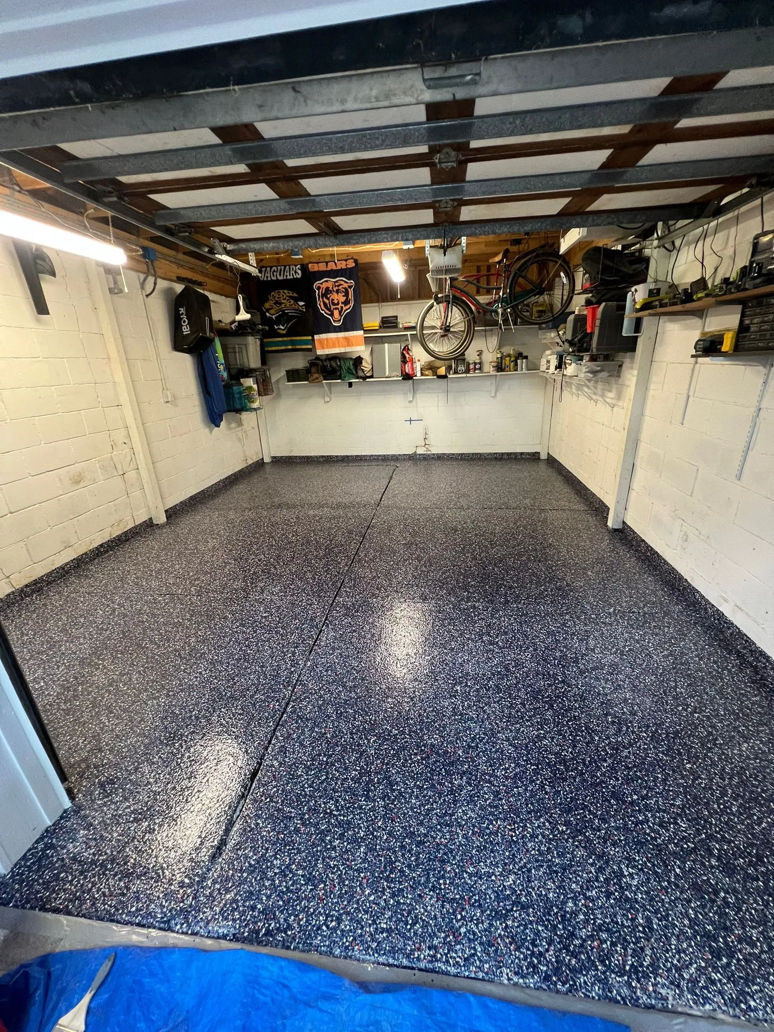 Blue and grey decorative flake floor in a home garage workshop with tools and bicycles