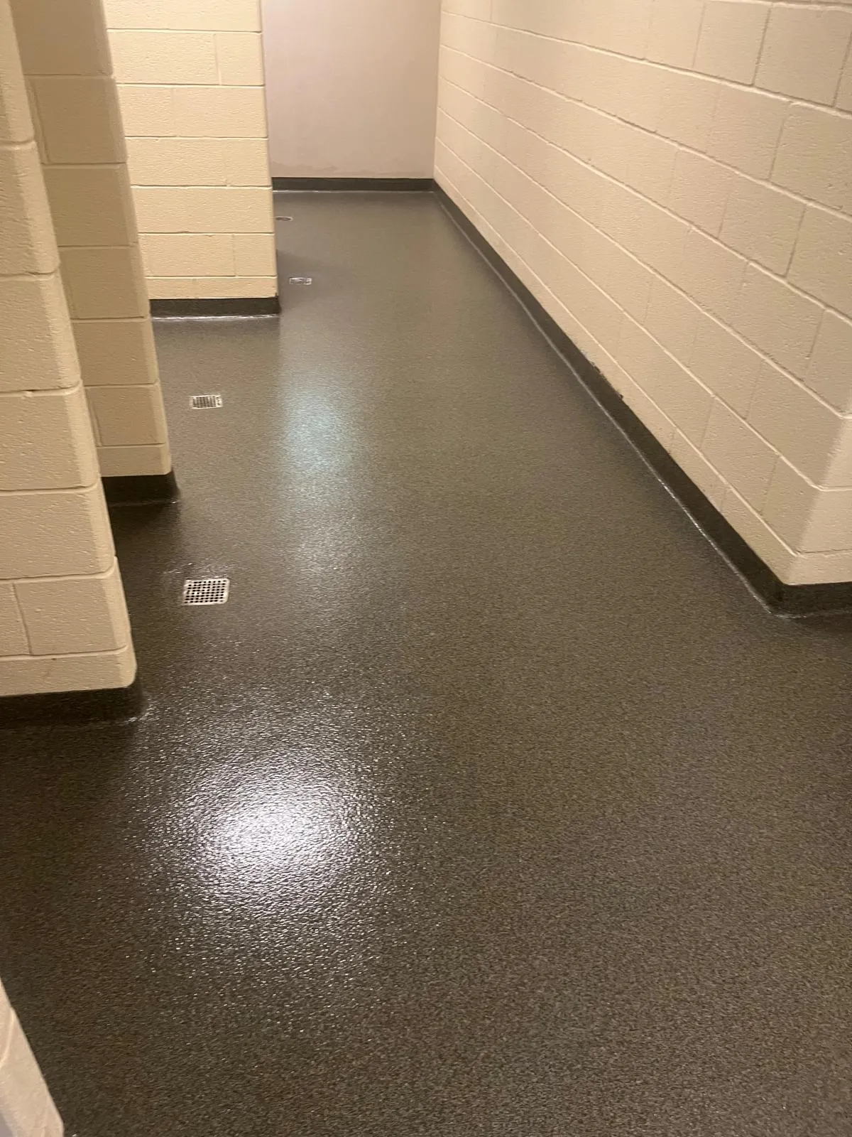 Grey decorative flake floor with integral cove base in an institutional restroom