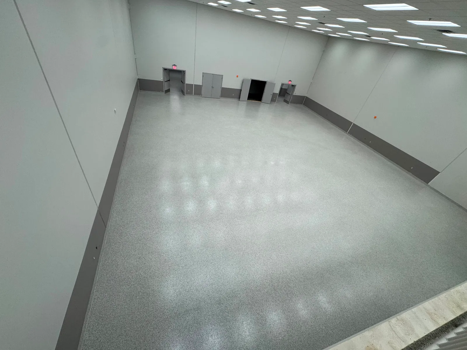 Grey decorative flake flooring in a laboratory with stainless cabinetry and bright overhead lighting