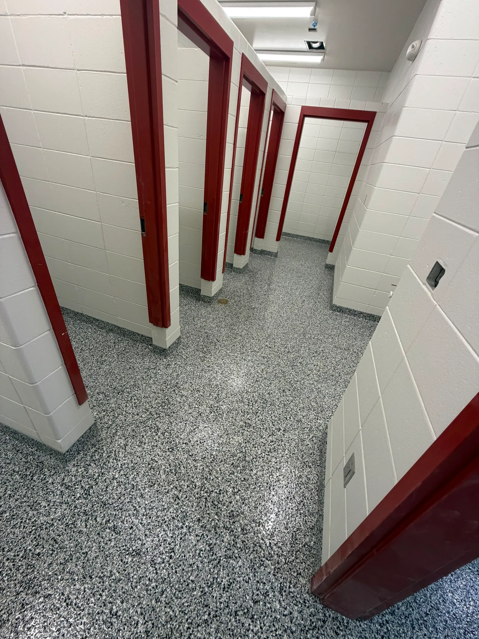Grey decorative flake flooring running between red locker banks in a school locker room