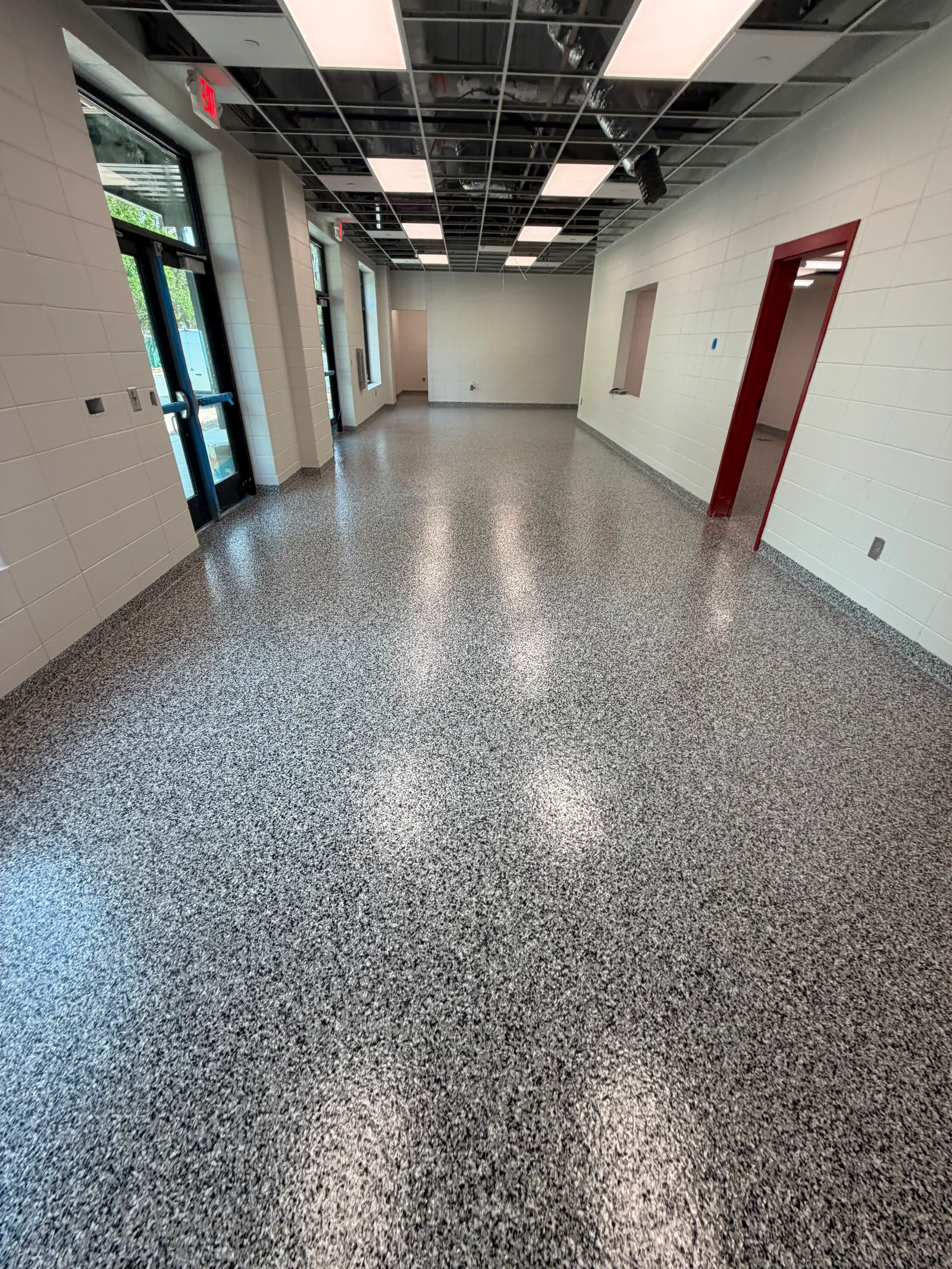 Glossy grey decorative flake floor in an open locker room with red support posts