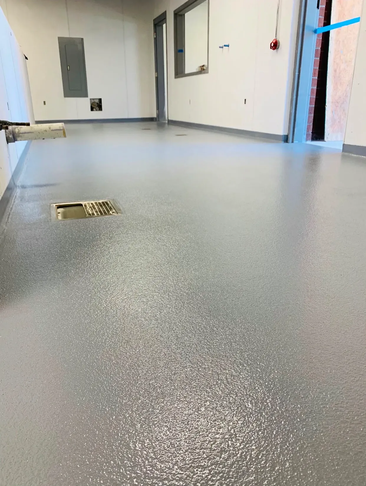 Textured quartz floor sloped to a central drain in a commercial wash-down area