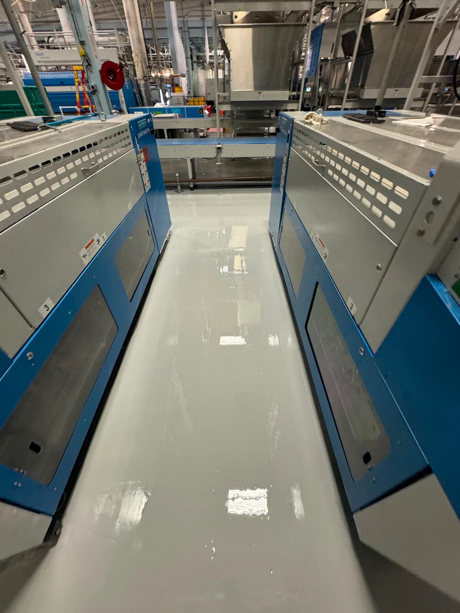 High-gloss resinous floor between blue equipment enclosures in an industrial facility