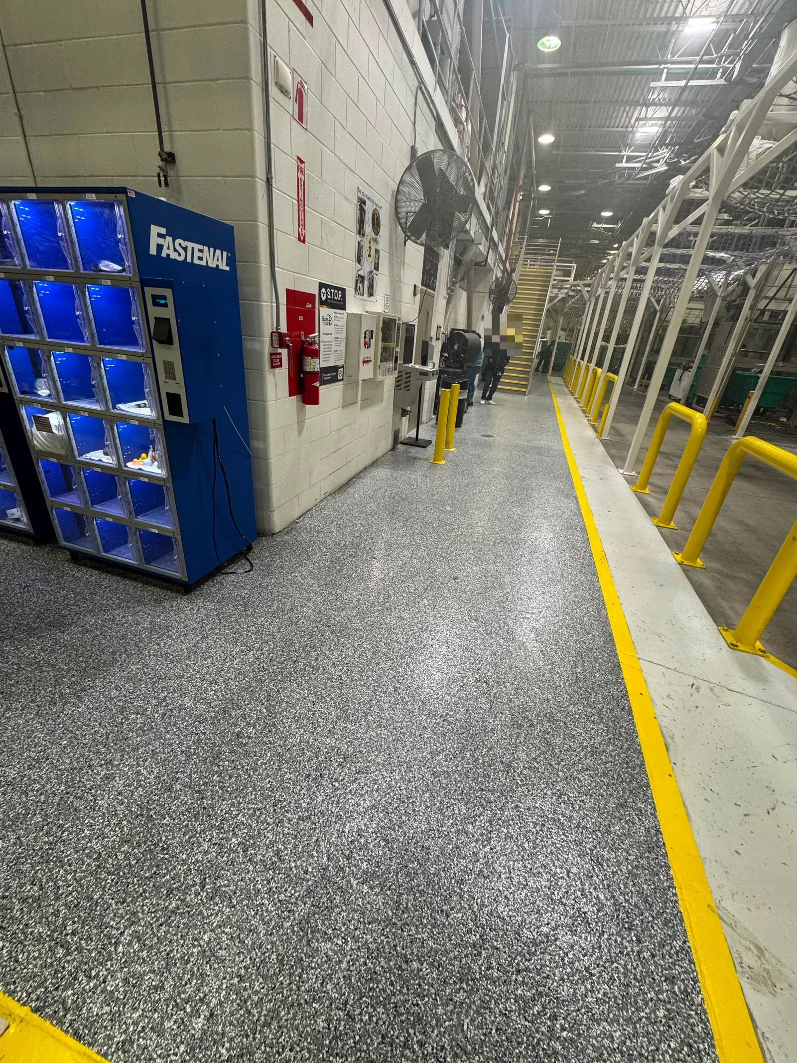 Grey flake industrial floor with yellow safety walk-lane striping in a manufacturing plant