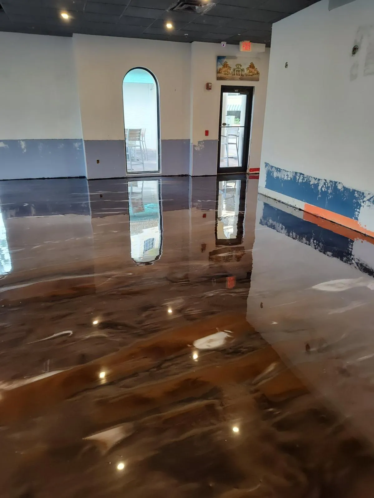 High-gloss copper and bronze metallic epoxy floor reflecting windows in an open residential interior