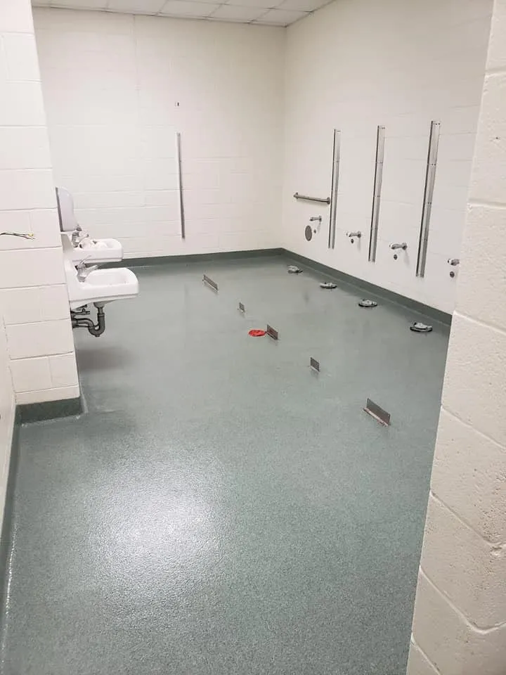 Grey quartz flooring in an institutional restroom with wall-mounted sinks and urinals