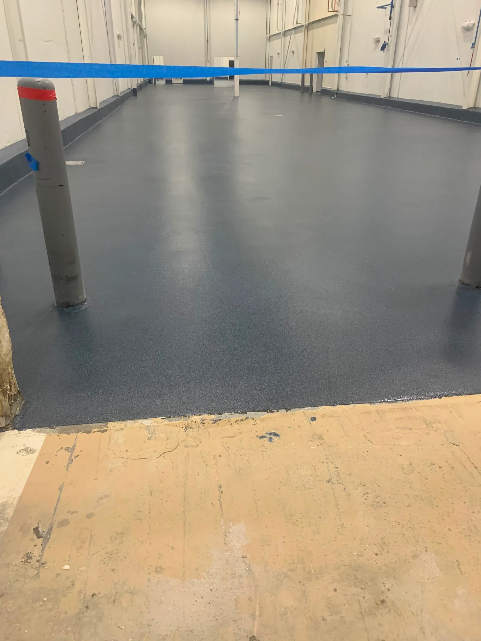 Blue-grey solid resinous floor with cove base in a commercial hallway