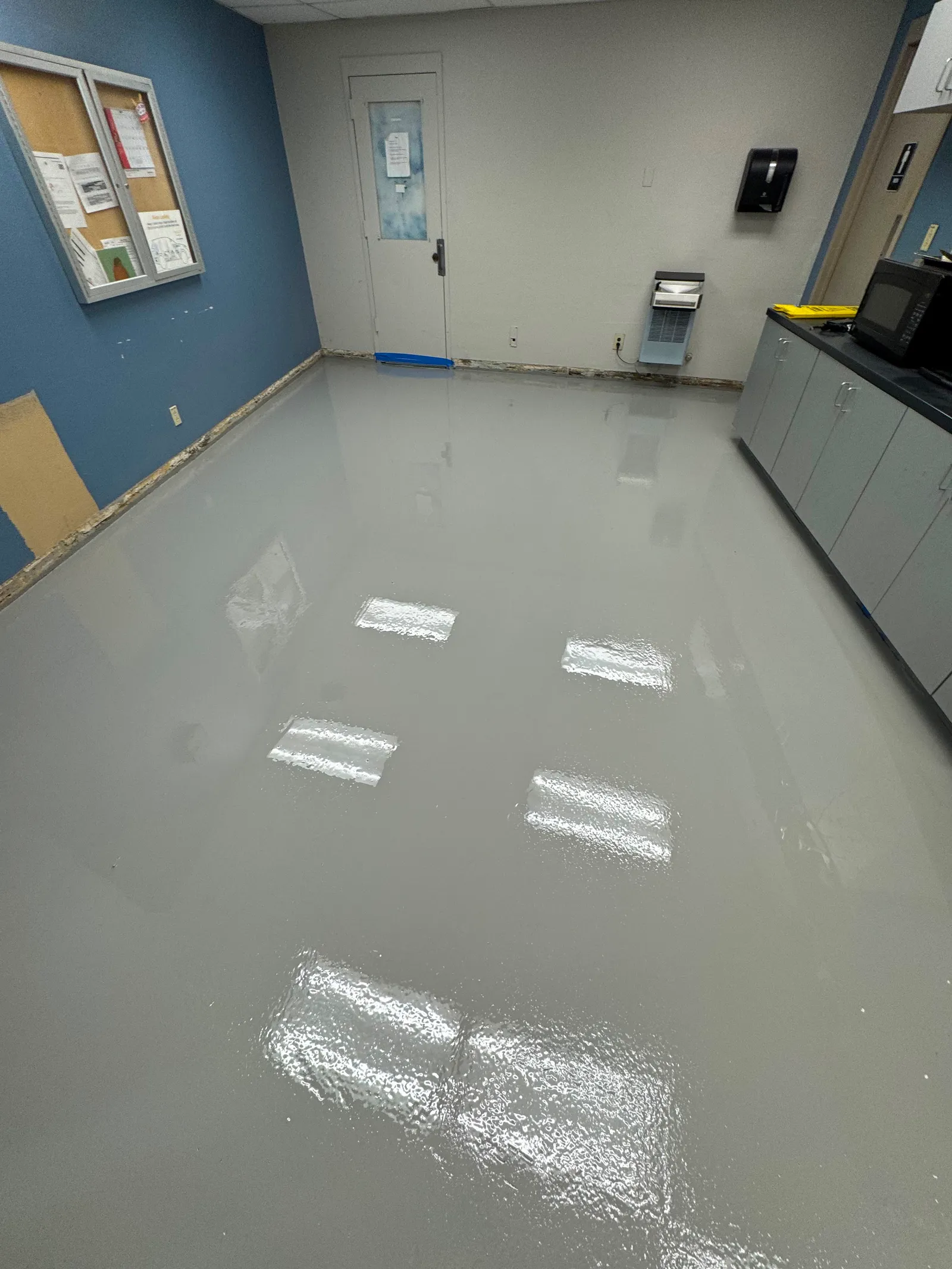 Glossy solid-color urethane floor coating reflecting lights in a commercial kitchen