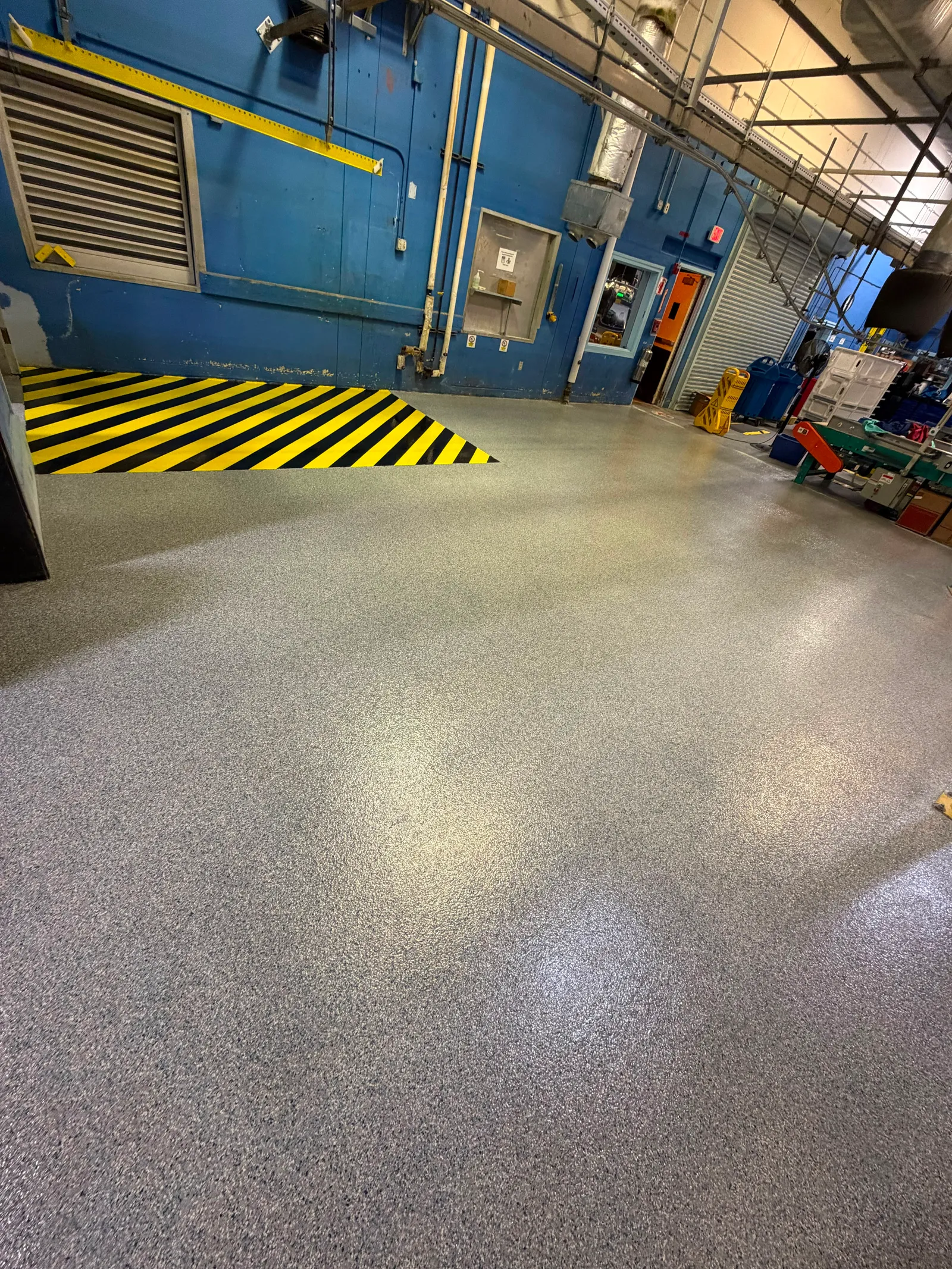 Grey flake warehouse floor with black-and-yellow chevron safety striping at a loading zone