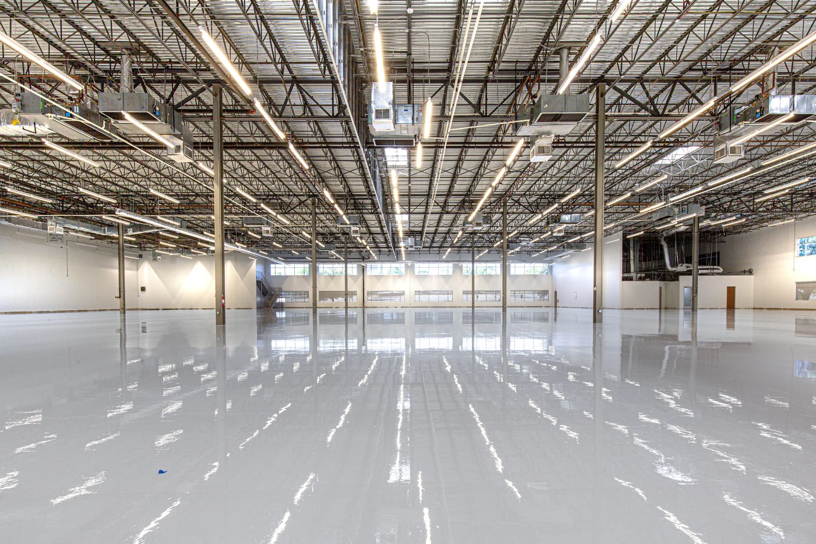 Expansive commercial floor finished with a glossy gray epoxy coating reflecting overhead lights